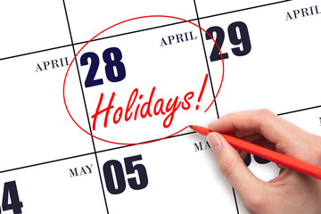 Hand drawing a red circle and writing the text Holidays on the calendar date 28 April. Important...