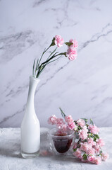 pink carnations in a white vase and coffee cups in a heart-shaped pink box,