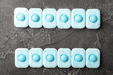 Water softener tablets on black texture background. Capsules for washing machines and dishwashers, preventing limescale. Place to copy.