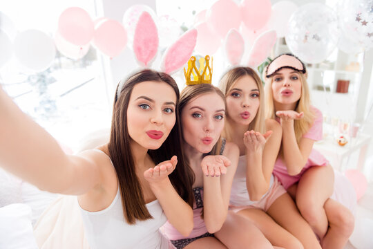Photo of four lovely pretty girls make selfie send air kiss pouted lips bedroom indoors