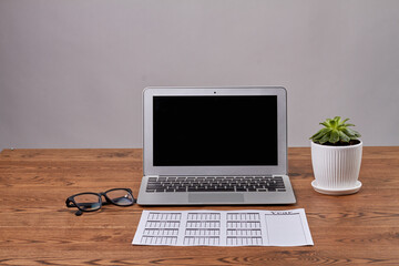 Business image of schedule book with glasses and laptop computer. Black laptop screen on wooden desk.