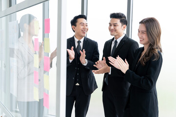 A group of Asian businessmen are gathering ideas to share ideas and offer ideas at a board in the office. with determination, determination and good fun