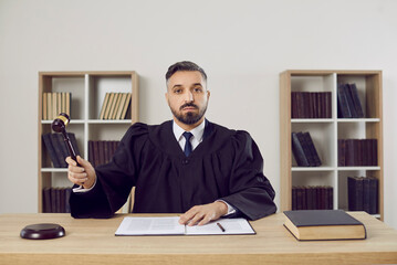 Portrait of young ethnic man judge in mantle strike hammer make verdict in court. Serious middle-aged prosecutor pronounce sentence or judgment. Law and order. Justice and jurisdiction concept. - obrazy, fototapety, plakaty
