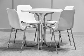 White chairs and table indoor set. Contemporary plastic furniture. Nobody