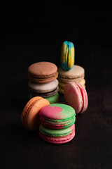 On a black background, a blurry image of multi-colored macaroons arranged in different ways.