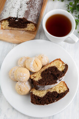 Fototapeta na wymiar Lemon chocolate cupcake and cookies in a plate, a cup of tea on a light table.