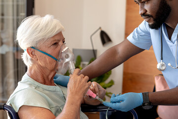 African american male health worker helping caucasian senior woman to use oxygen mask