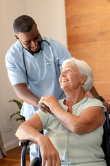 Obraz premium African american male health worker supporting caucasian senior woman sitting on the wheelchair