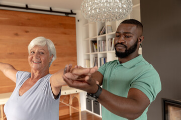 African american male physiotherapist helping caucasian senior woman to perform stretching exercise - Powered by Adobe