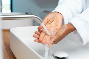 Mid section of african american woman washing her hands in the sink at home - Powered by Adobe