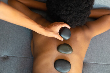 African american woman woman receiving hot stone massage at home