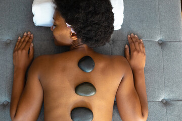 African american woman woman with eyes closed receiving hot stone massage at home