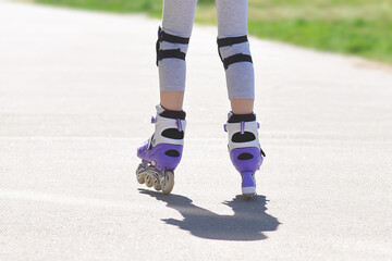 Fototapeta na wymiar Roller skating. Close-up of the legs of a child rollerblading outdoors. Education, sports, leisure.