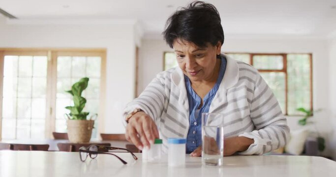 Asian senior woman checking her medicine containers in the living room at home