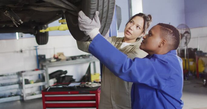 Video of two diverse female car mechanics wheel