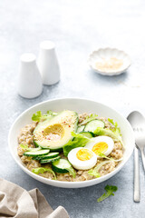Fototapeta na wymiar Oatmeal porridge with boiled egg, cucumber and avocado