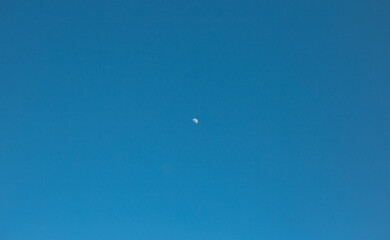 the moon is visible in the blue sky during the day