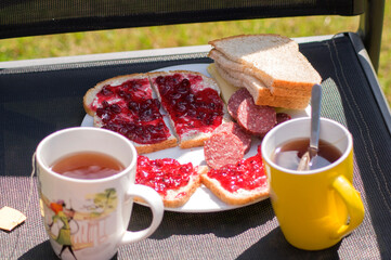 breakfast in the garden on a chair two sandwiches with sausage and butter jam 