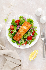 Grilled salmon fish fillet and fresh vegetable salad with tomato, red onion and lettuce