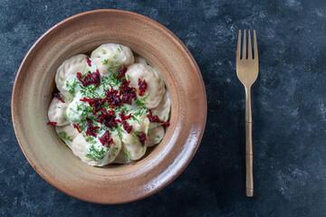 Appetizing dumplings stuffed with potatoes and mushrooms with sour cream, green dill and beetroot