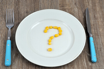 Point d'interrogation avec des grains de maïs dans une assiette