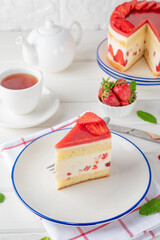 Fraisier mousse cake. Strawberry cake with biscuit, mousse and jelly on a white wooden background. Summer dessert. Selective focus. Copy space.