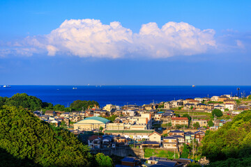 Afternoon sun hits small coastal village as clouds billow in distance