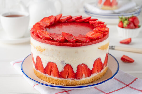 Fraisier mousse cake. Strawberry cake with biscuit, mousse and jelly on a white wooden background. Summer dessert. Selective focus. Copy space.