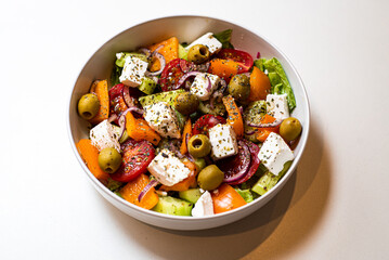 Fresh sliced vegetables for salad in a plate on a white background