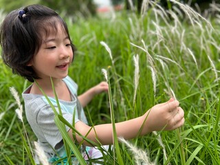 Beautiful little cute girl is picking up flower in the grass field with copy space