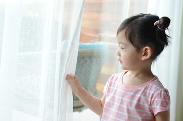 cute little girl is holding the white curtain with copy space