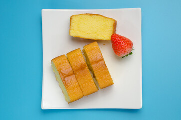 Blue background and white milk in glass, cake in white plate