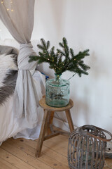 spruce branch in glass vase on bedside table. Christmas decor ideas. 