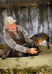 A hunter with a black duck taken while floating a river 