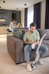Man taking apart vacuum cleaner sitting on sofa