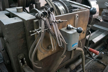 Fototapeta premium Closeup of a measuring special equipment like calipers, dividers & compass of old Lathe Machinery. Vintage Industrial Machinery in a old factory. Selective focus. 