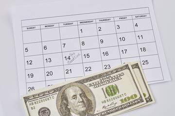 Tax deadline concept. Dollar banknotes and calendar with marked date. Top view flat lay.