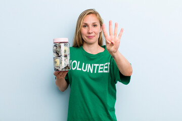 young adult blonde woman smiling and looking friendly, showing number four. volunteer and donation...