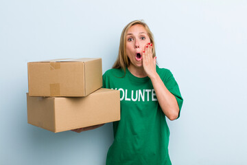 young adult blonde woman feeling shocked and scared. volunteer and donation concept