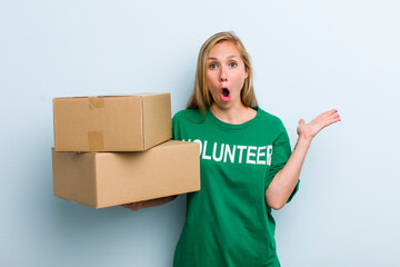 young adult blonde woman looking surprised and shocked, with jaw dropped holding an object....
