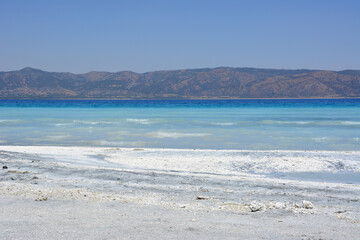 Salda lake beach with white and gray sand, blue water and hills on background