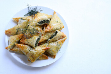 Cucina tradizionale greca. Spanakopita, triangolo di pasta fillo con spinaci e feta su sfondo...