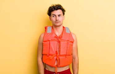 young handsome guy feeling sad, upset or angry and looking to the side. life jacket and boat concept