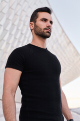 Young ethnic man against modern building