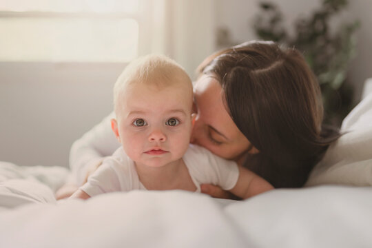 Mother and baby on white bed at home