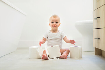 Adorable baby boy playing with toilet paper