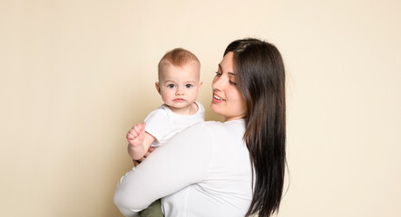 Cheerful baby boy toddler with his mother on yellow studio background