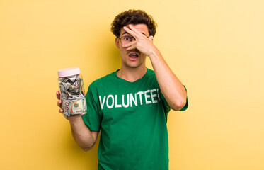 young handsome guy looking shocked, scared or terrified, covering face with hand. donation and...