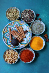 Aromatic herbs and spices. Decorative bowls full of various spices. Mediterranean lifestyle still life. Vibrant colors of paprika, turmeric powder, pepper, nuts, anise, cardamom, bay leaf, dry herbs.