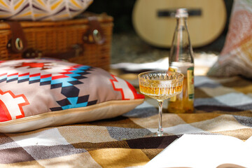 Outdoor picnic with Glass of lemonade on checkered beige rug and pillow. camping, vacation. Rest alone